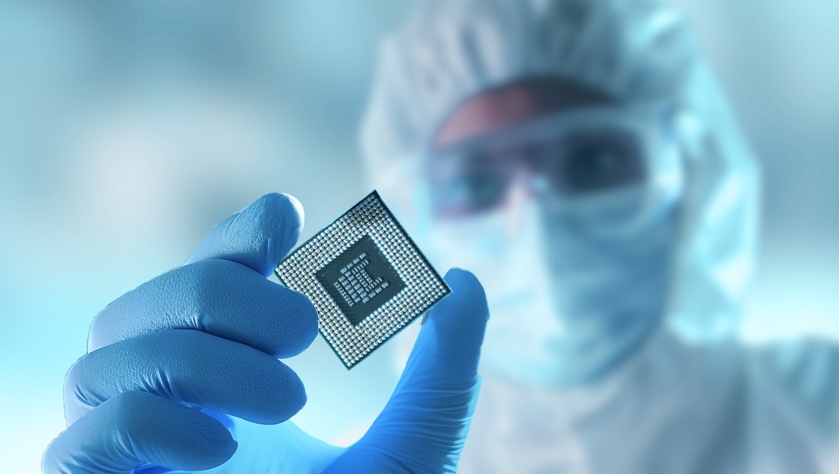 A person in a cleanroom suit inspects a computer chip. It is about high-purity pfa tubing products for semiconductor technologies made in Germany by APT from Düsseldorf